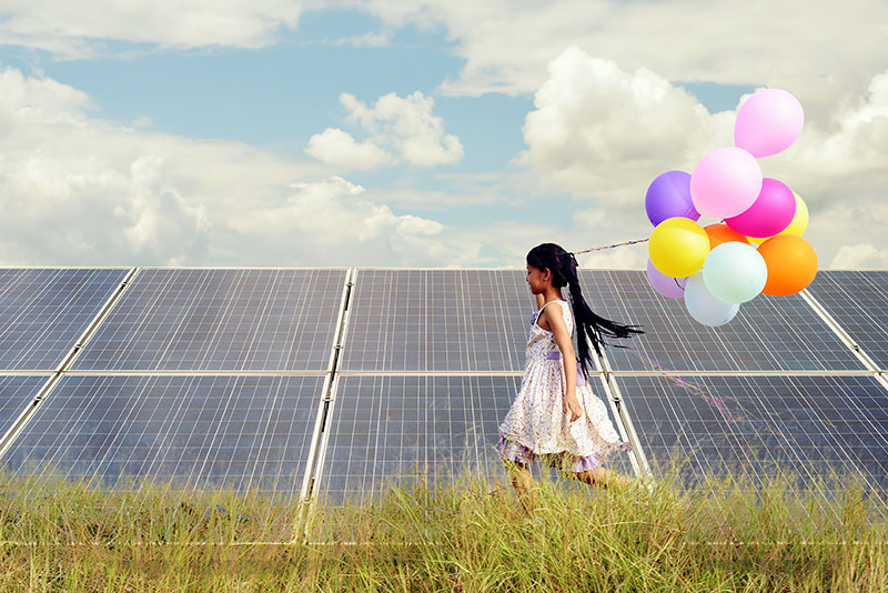 Little girl with Ballons in front of solar panels